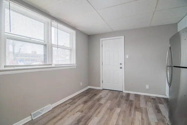 a view of an empty room with wooden floor and closet