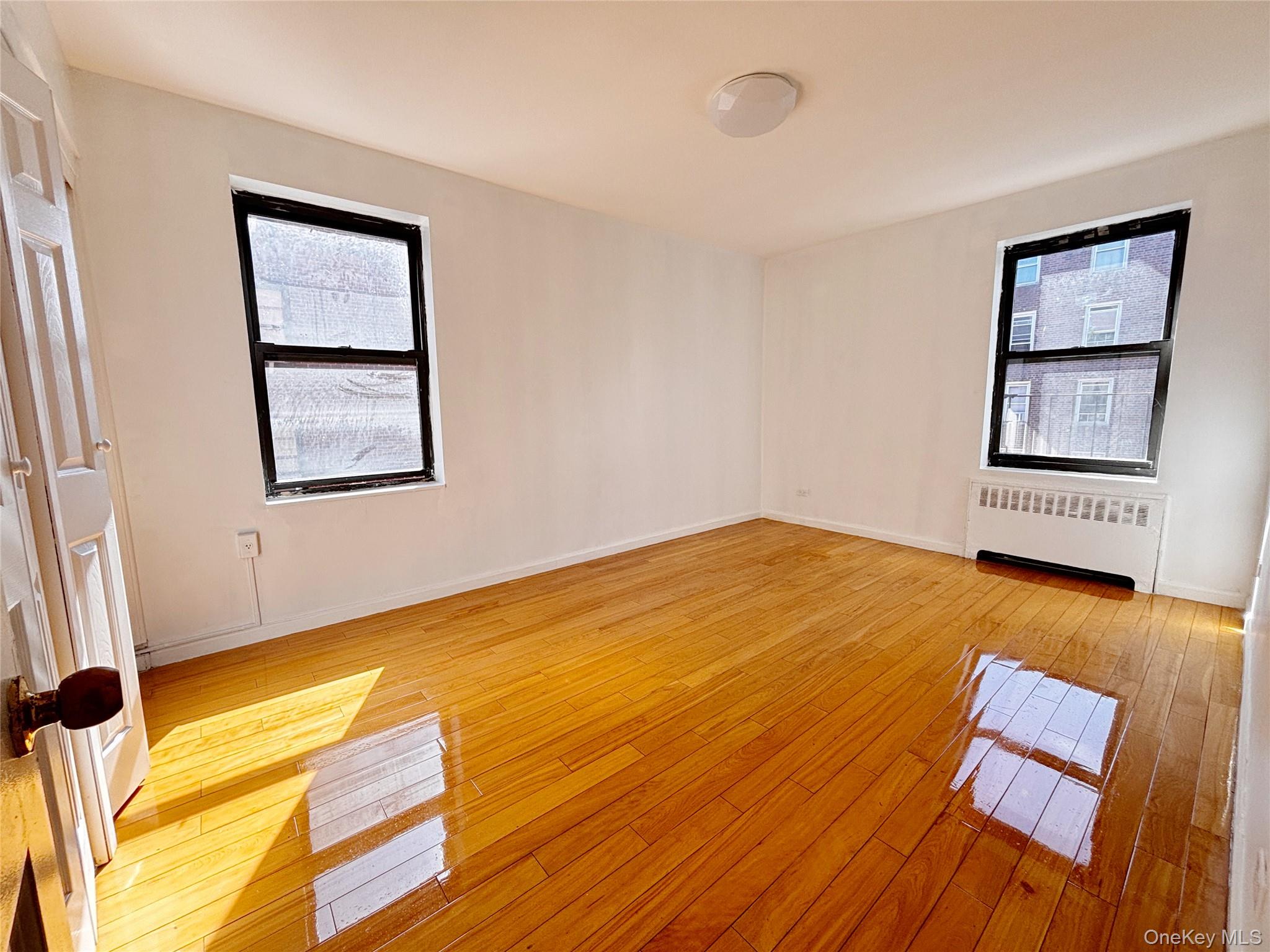 44-25 Macnish Street, Unit 4A Queens, NY 11373 - Photo 6 of 12 Spare room with radiator heating unit and light wood-style flooring