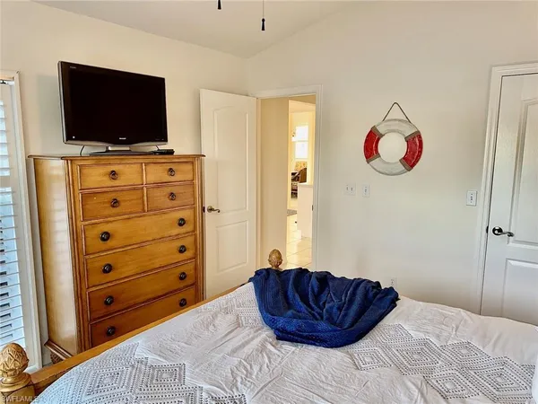 a bedroom with a bed and a flat tv screen on dresser