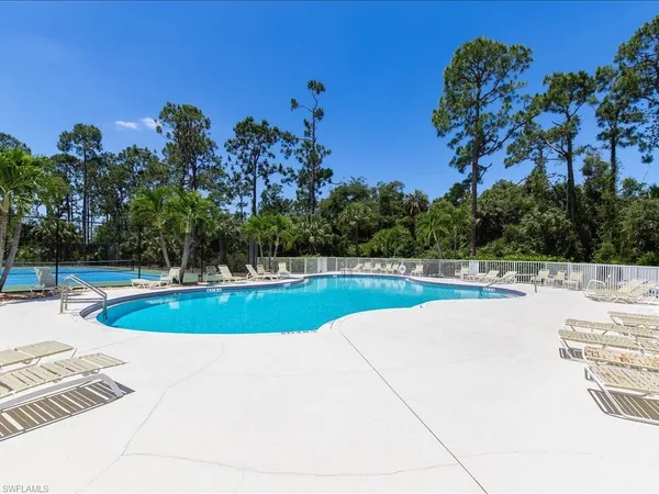 a view of house with swimming pool outdoor seating and trees