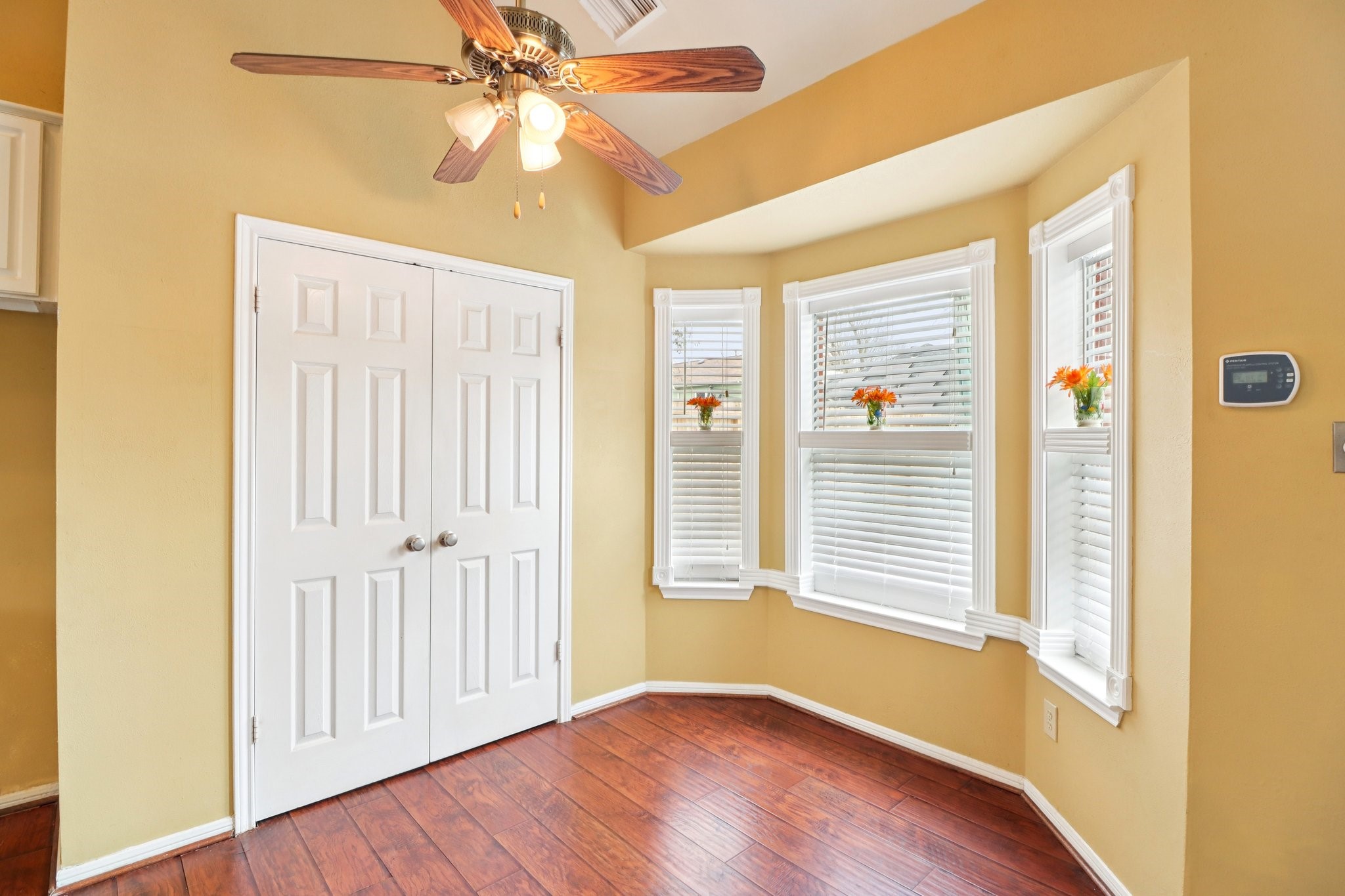 24 Dover Drive Conroe, TX 77304 - Photo 14 of 39 This bright breakfast room features a cozy bay window, perfect for enjoying natural light. It has warm, wood-style flooring, a ceiling fan, and a pantry with double doors for extra storage.