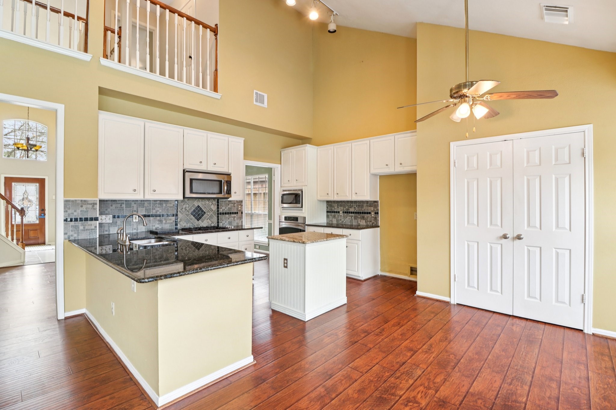 24 Dover Drive Conroe, TX 77304 - Photo 15 of 39 This bright kitchen features high ceilings, granite countertops, and modern appliances. It opens to a spacious family room with a ceiling fan, creating a welcoming space for cooking and entertaining.