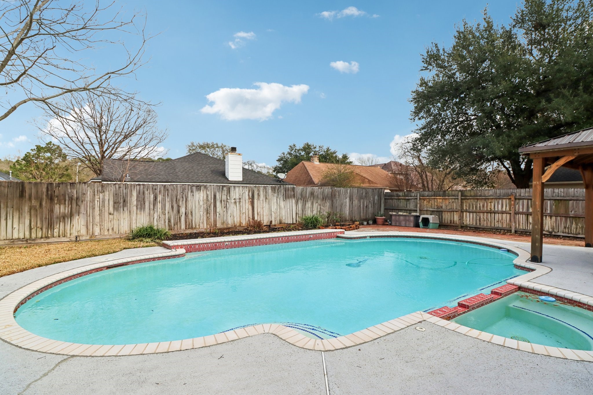 24 Dover Drive Conroe, TX 77304 - Photo 36 of 39 Spacious backyard with a large swimming pool and spa, surrounded by a wooden fence for privacy. Features a covered patio area, perfect for relaxation and entertaining.