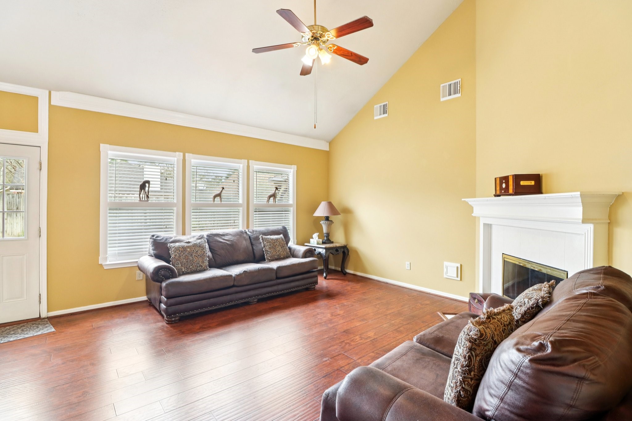 24 Dover Drive Conroe, TX 77304 - Photo 10 of 39 Spacious family room with high ceilings and plenty of natural light. Features wood floors, a cozy fireplace, and a warm color palette. Ideal for relaxation and entertaining.