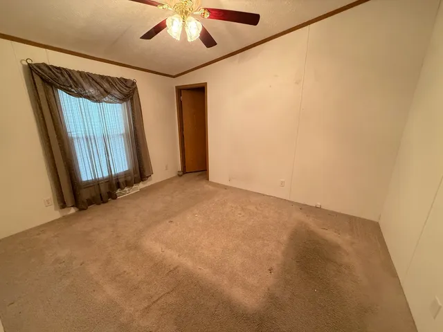 an empty room with a window and a ceiling fan
