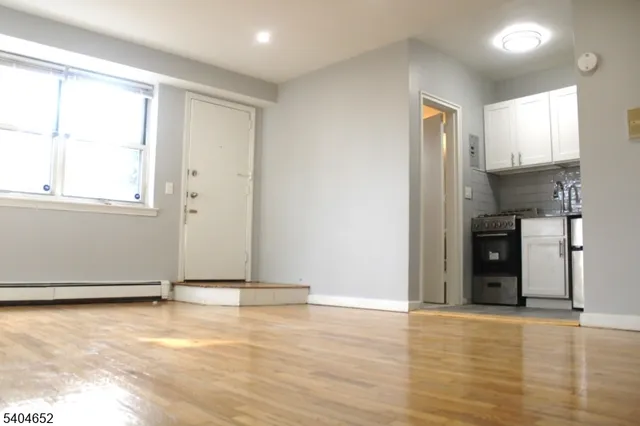a view of an empty room with window and wooden floor