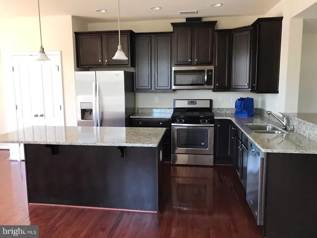 a kitchen with stainless steel appliances wooden cabinets a stove a sink and a refrigerator