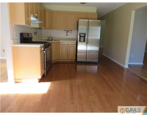 36 Gable Court Old Bridge, NJ 07747 - Photo 8 of 22 a kitchen with kitchen island a counter top space a sink wooden floor and a refrigerator