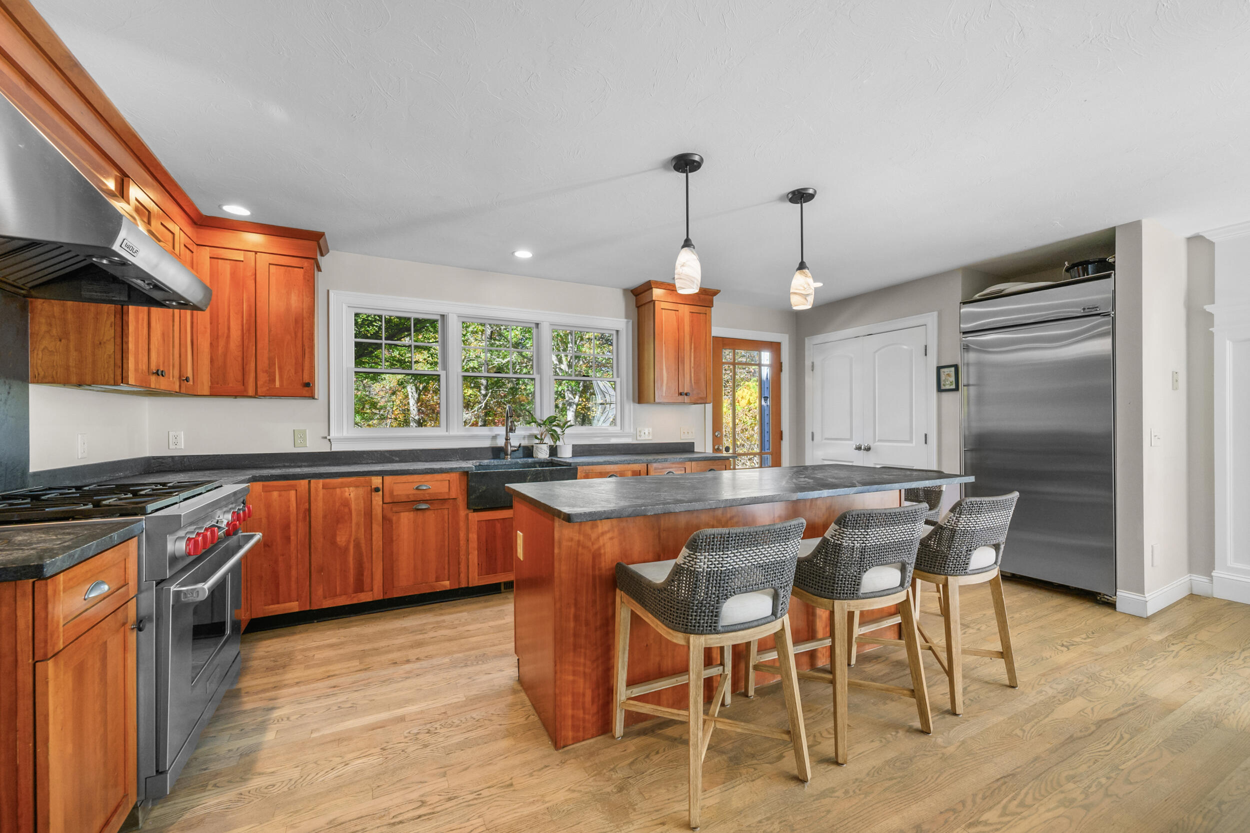 250 The Plains Road West Barnstable, MA 02668 - Photo 10 of 44 a kitchen with stainless steel appliances granite countertop a stove top oven a sink a dining table and chairs with wooden floor