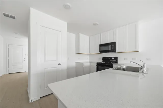 a kitchen with a sink a microwave and cabinets