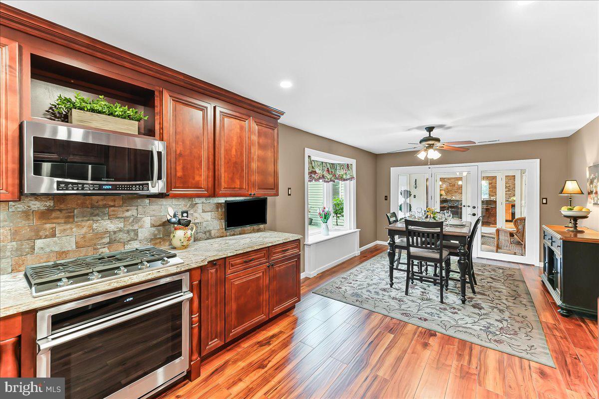 780 Tannery Drive Wayne, PA 19087 - Photo 27 of 59 a kitchen with stainless steel appliances granite countertop a stove top oven a sink dishwasher a dining table and chairs with wooden floor