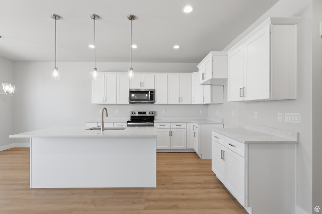 677 East 800 S Street Springville, UT 84663 - Photo 4 of 35 Kitchen with white cabinets, stainless steel appliances, a kitchen island with sink, light wood-style floors, and light stone counters