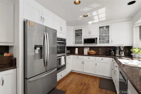 a kitchen with granite countertop a sink white cabinets and a large window
