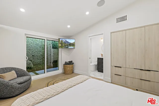 a spacious bedroom with a bed and wooden floor