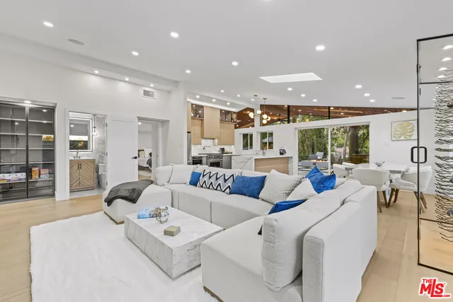 a kitchen with stainless steel appliances kitchen island granite countertop a refrigerator oven a sink dishwasher and white cabinets with wooden floor