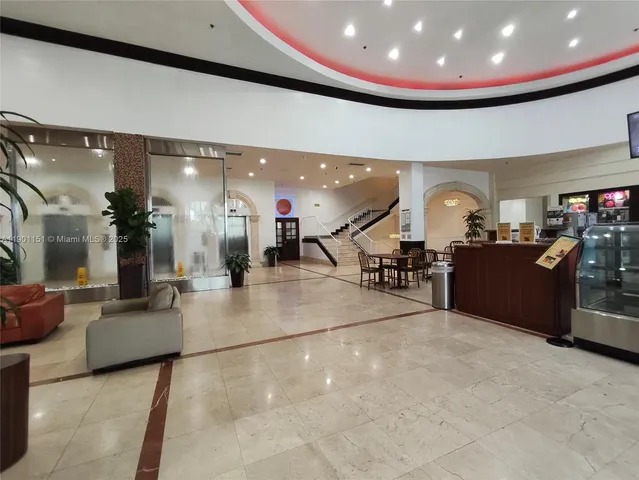 a lobby with a chandelier and couches with large mirror