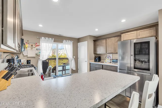 a kitchen with stainless steel appliances granite countertop a refrigerator a sink dishwasher a dining table and chairs with wooden floor