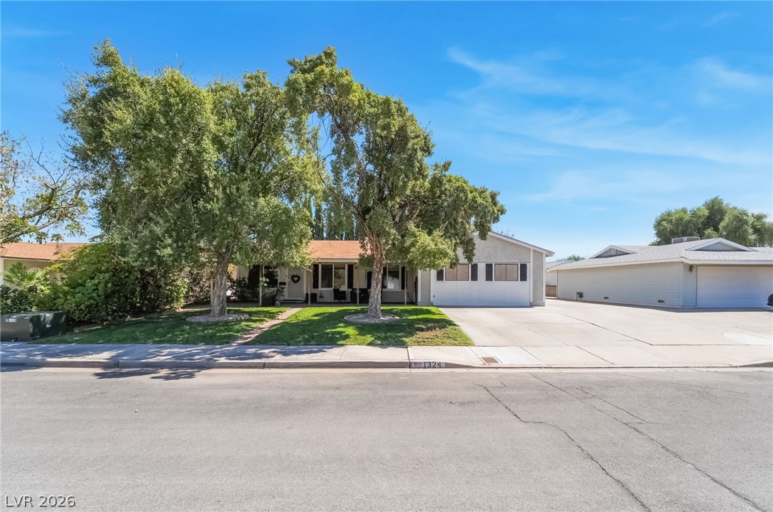 Mature shade trees frame the classic facade of this single-story home with an attached garage.