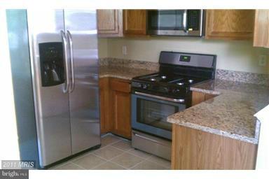 9104 Piper Ridge Court Lanham, MD 20706 - Photo 2 of 4 a kitchen with granite countertop a stove and a microwave