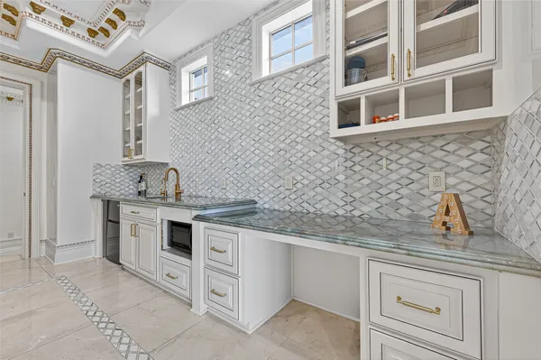 a large kitchen with granite countertop a stove a sink a refrigerator and glass cabinets