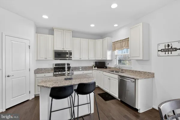 a kitchen with stainless steel appliances granite countertop a table chairs and refrigerator