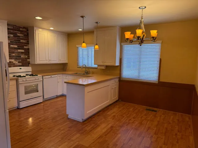 a kitchen with stainless steel appliances granite countertop a sink a stove and a wooden floor