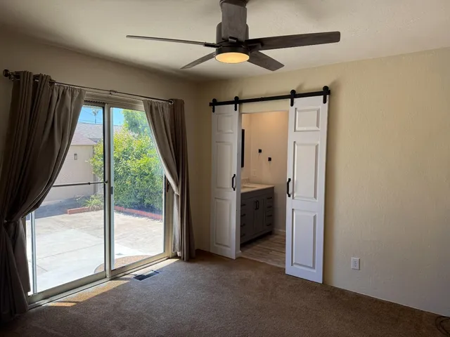 a view of empty room with window and ceiling fan