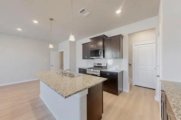 a kitchen with stainless steel appliances a stove top oven a sink and a refrigerator