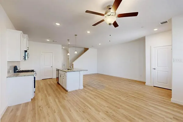 a kitchen with granite countertop a sink a stove top oven a counter space and cabinets