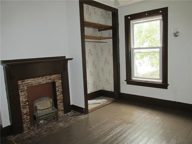 an empty room with wooden floor a fireplace and windows