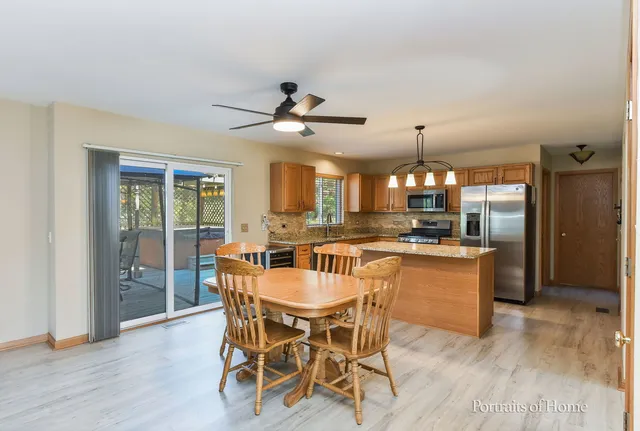 a dining area with chandelier and wooden floor