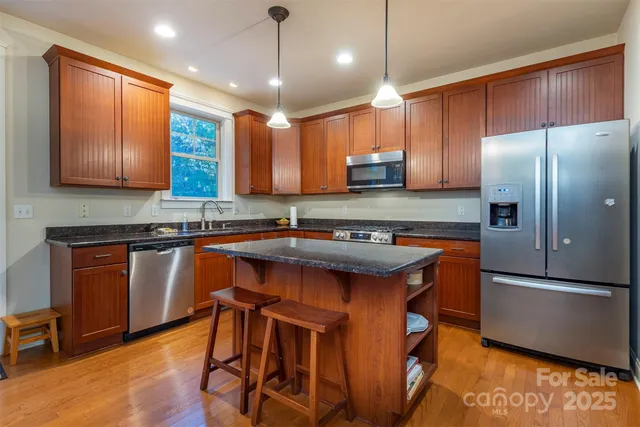 a kitchen with stainless steel appliances granite countertop a sink a stove a refrigerator and island
