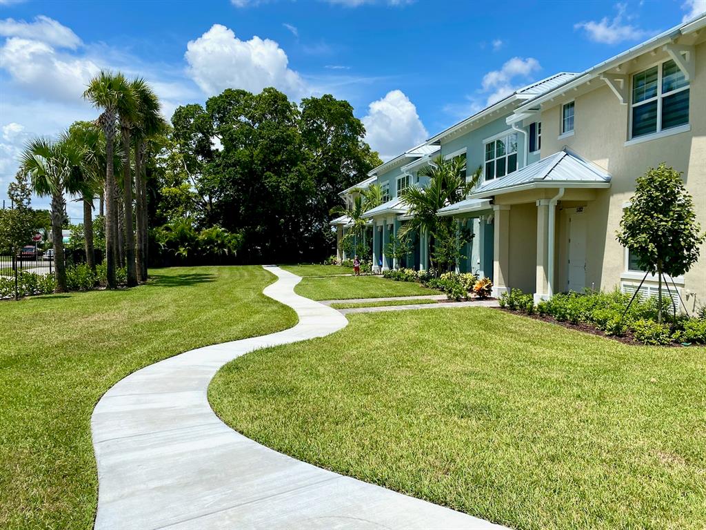 a view of a white house with a swimming pool and lawn chairs with plants