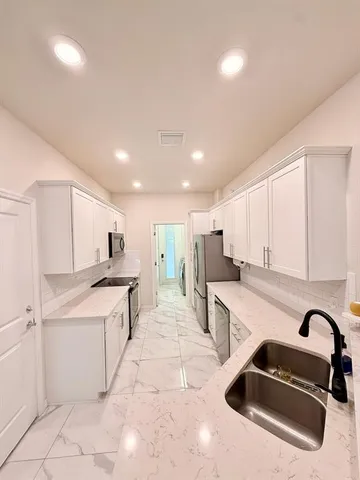 a kitchen with stainless steel appliances kitchen island granite countertop a sink and white cabinets