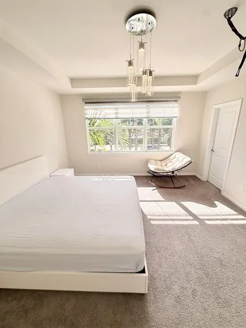 a spacious bedroom with a bed and chandelier