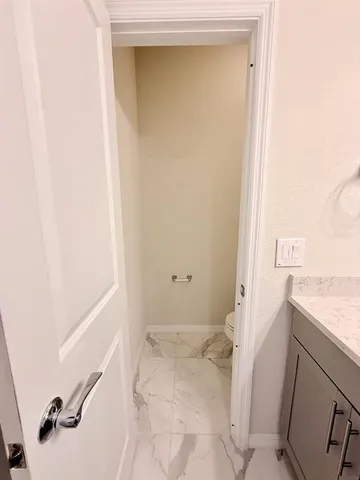 a white toilet sitting next to a white wall