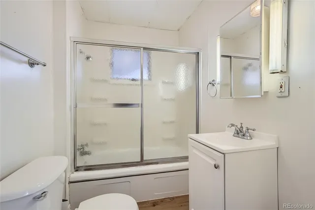 a bathroom with a shower sink vanity mirror and toilet