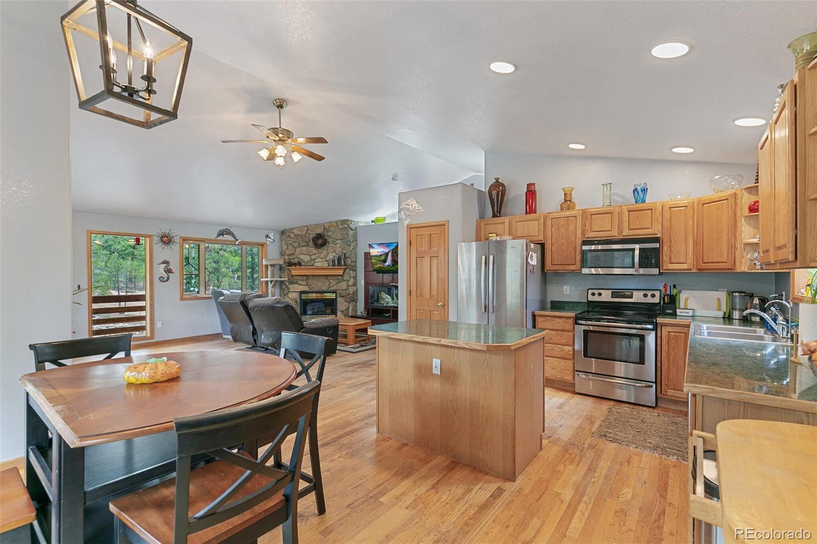 30 Bristlecone Circle Bailey, CO 80421 - Photo 12 of 35 a kitchen with stainless steel appliances granite countertop a stove top oven a refrigerator a dining table and chairs with wooden floor