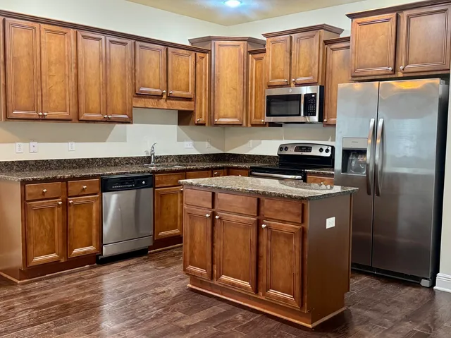 a kitchen with stainless steel appliances granite countertop a stove a microwave and a refrigerator