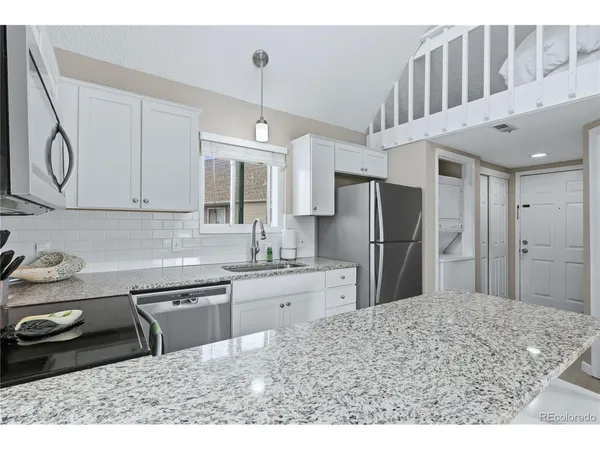 a kitchen with stainless steel appliances kitchen island granite countertop a sink refrigerator and cabinets