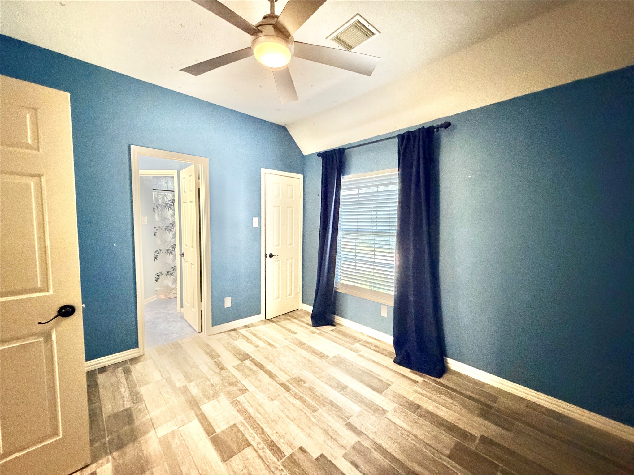 20110 Forest Drive Spring, TX 77388 - Photo 34 of 43 Experience tranquility in Bedroom 3, featuring soothing blue walls, sleek wood-look flooring, and abundant natural light perfect for restful nights.