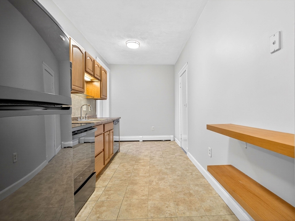 12 Ransom Road, Unit 7 Boston, MA 02135 - Photo 3 of 4 a kitchen with granite countertop a sink and a stove top oven