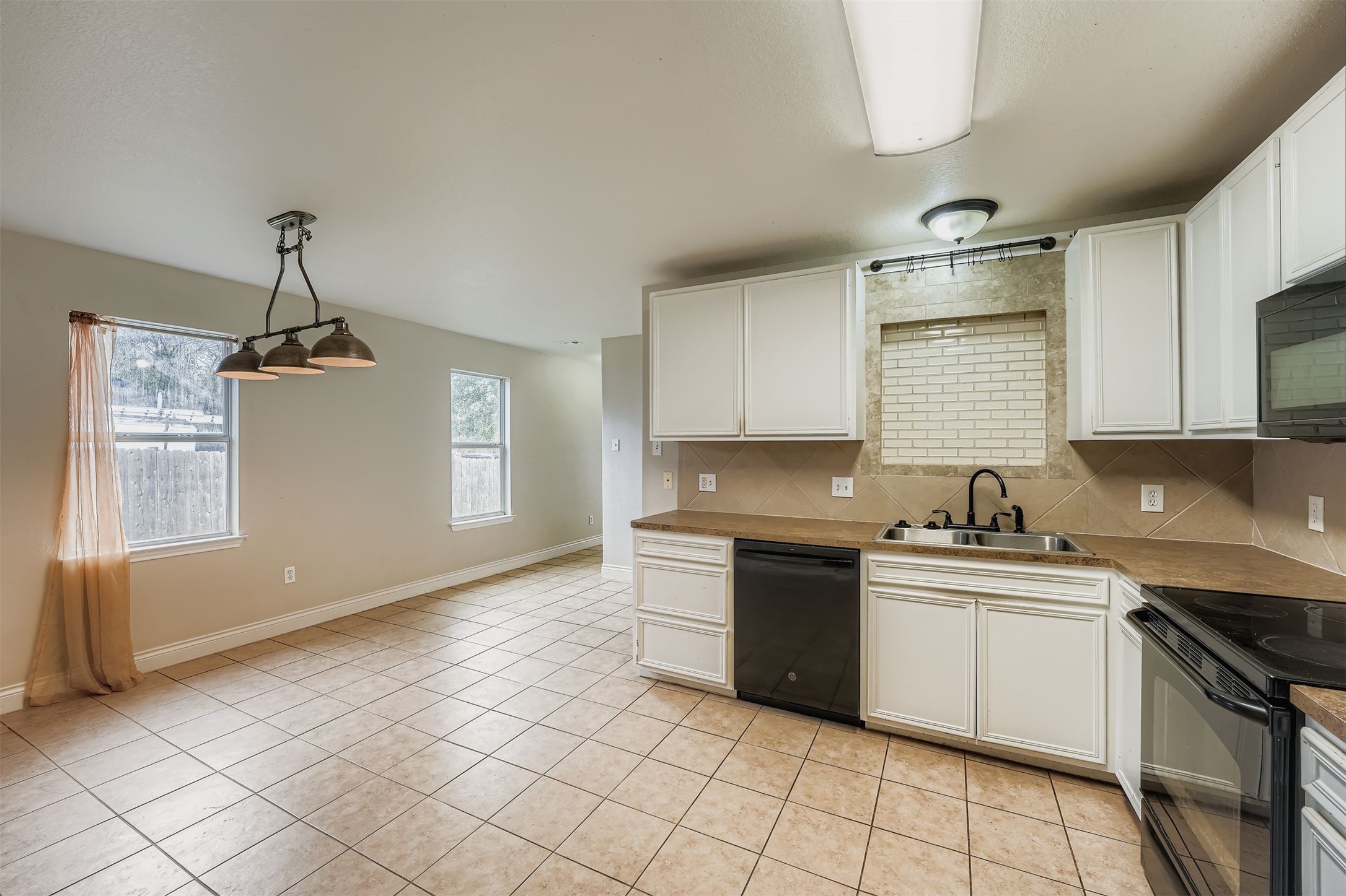 304 South Main Street Elgin, TX 78621 - Photo 13 of 25 Kitchen with decorative backsplash, black appliances, and white cabinetry