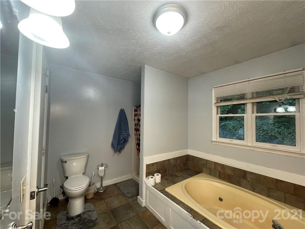 263 Cedar Rock Road Waynesville, NC 28786 - Photo 17 of 20 a bathroom with a granite countertop toilet a sink and bathtub