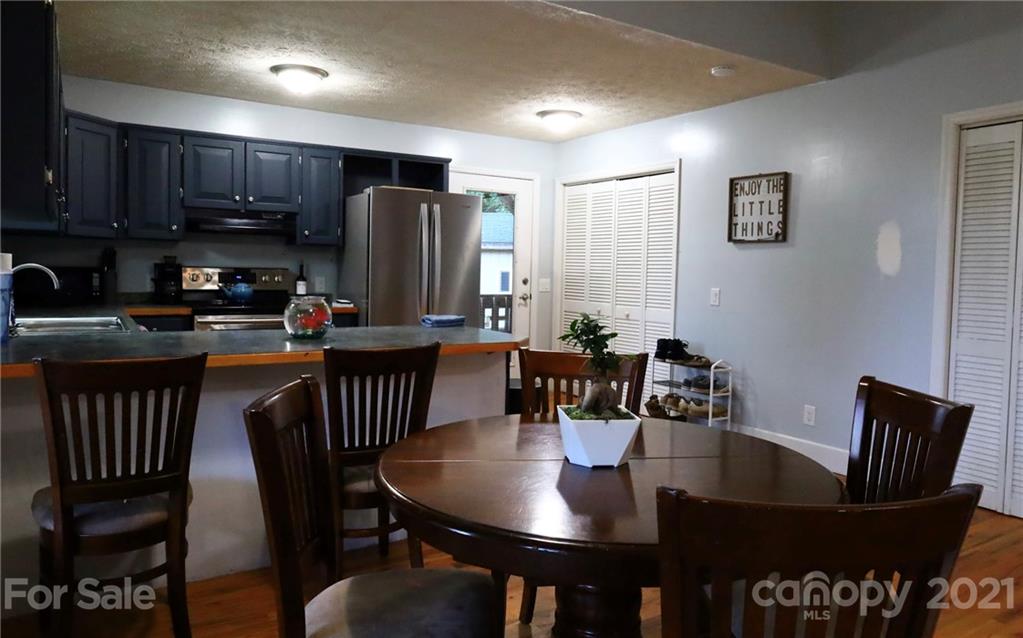 263 Cedar Rock Road Waynesville, NC 28786 - Photo 3 of 20 a kitchen with granite countertop a dining table chairs and a refrigerator