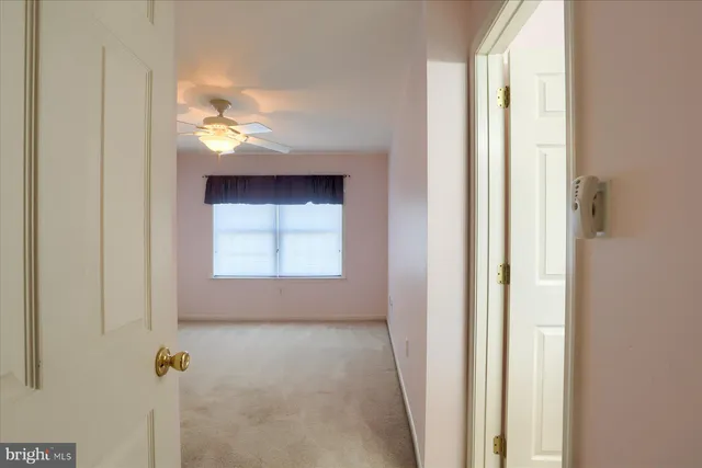 an empty room with a chandelier fan and windows