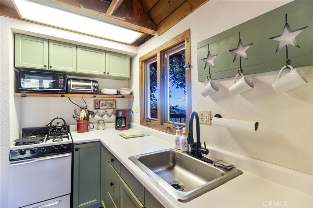 24387 Rocky Point Road Idyllwild, CA 92549 - Photo 26 of 29 a kitchen with stainless steel appliances granite countertop a sink and a refrigerator