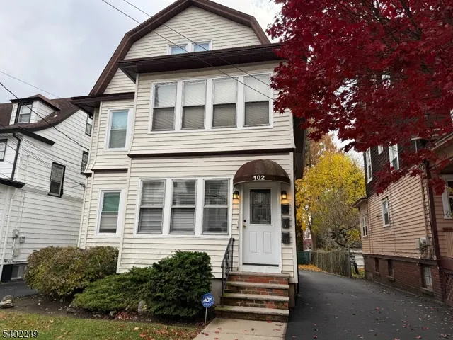 a view of a white house with large windows and a tree