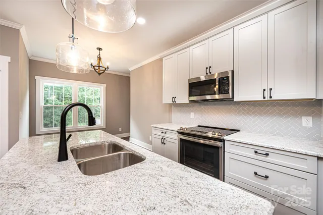 a kitchen with granite countertop a stove a sink and a microwave