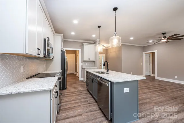 a kitchen with stainless steel appliances granite countertop a sink a stove and a wooden floors